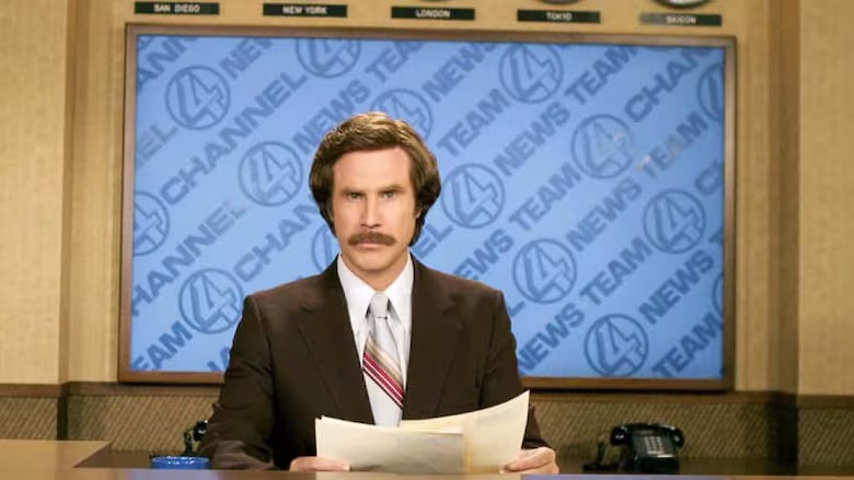 Ron Burgundy sitting behind a television anchor desk in the film Anchorman.