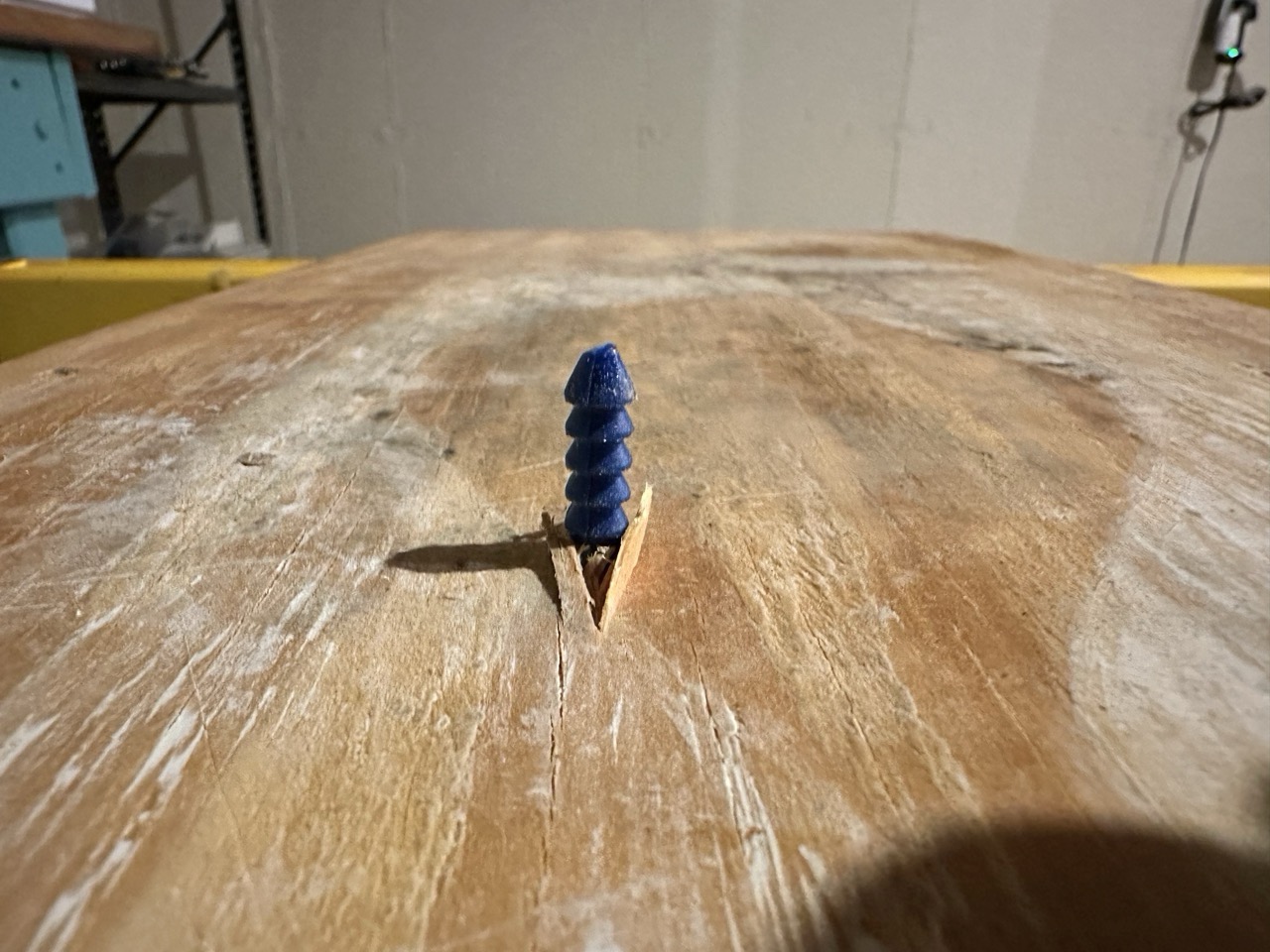 A wall anchor screwed into a board
